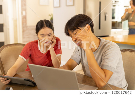 Using laptop and tablet, young asian brother and sister working together  at home 120617642