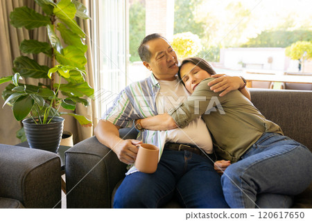 Relaxing on couch, couple hugging and enjoying coffee in cozy living room 120617650