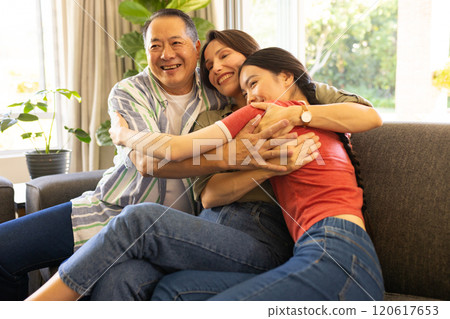 Family hugging and smiling on couch, enjoying quality time together 120617653