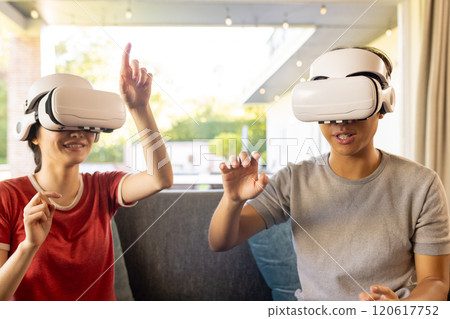 Using VR headsets, couple enjoying virtual reality experience at home Using VR headsets, couple enjoying virtual reality experience at home 120617752