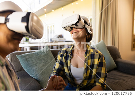 Using VR headsets, couple enjoying virtual reality experience at home Using VR headsets, couple enjoying virtual reality experience at home 120617756