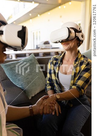 Using VR headsets, couple holding hands and enjoying virtual reality experience 120617761