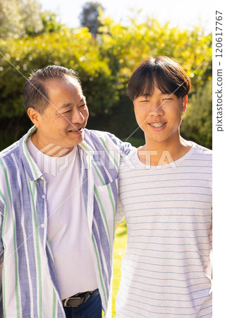 asian father and son smiling together, enjoying quality time outdoors in garden 120617767
