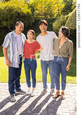 Smiling family standing together outdoors, enjoying quality time in garden Smiling family standing together outdoors, enjoying quality time in garden 120617768