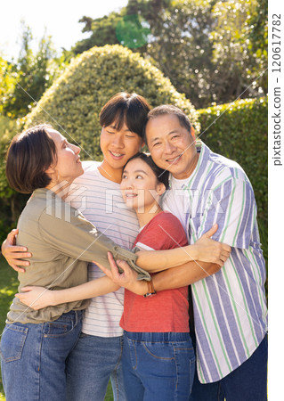 Smiling family with teenagers hugging together outdoors, enjoying quality time in garden Smiling family with teenagers hugging together outdoors, enjoying quality time in garden 120617782