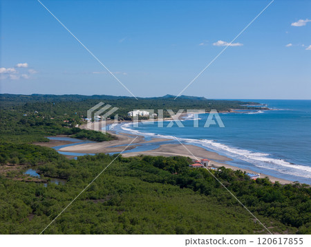 Scenic coastal view showcasing lush greenery and waves along serene beach 120617855