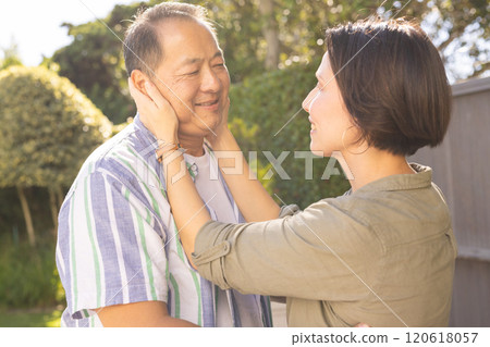 Woman touching man face, sharing tender moment outdoors in garden Woman touching man face, sharing tender moment outdoors in garden 120618057