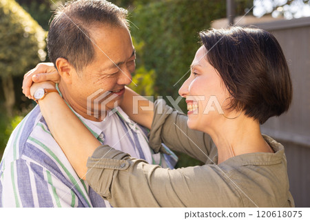 Smiling multiracial middle-aged couple embracing outdoors, enjoying quality time together in garden 120618075