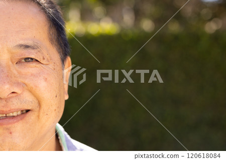 Smiling asian middle-aged man outdoors with greenery in background, enjoying sunny day Smiling asian middle-aged man outdoors with greenery in background, enjoying sunny day 120618084