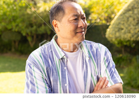 Smiling asian middle-aged man in casual shirt standing outdoors in garden, enjoying sunny day Smiling asian middle-aged man in casual shirt standing outdoors in garden, enjoying sunny day 120618090