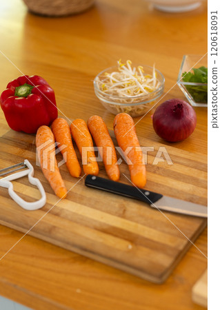 preparing fresh vegetables, chopping carrots, bell pepper, and onion on cutting board 120618091