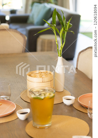 Dining table set with iced tea, bamboo steamer, and small dishes for family meal Dining table set with iced tea, bamboo steamer, and small dishes for family meal 120618094