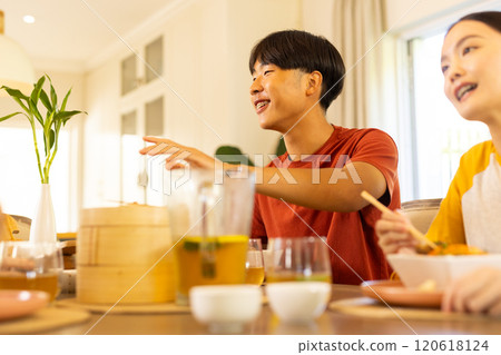 At home, Enjoying meal together, multiracial family sitting at dining table and smiling happily 120618124