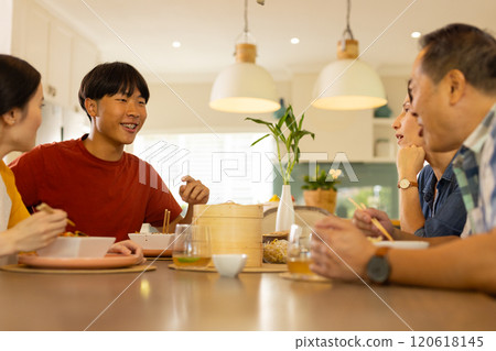 At home, asian family enjoying meal together, talking and smiling around dining table At home, asian family enjoying meal together, talking and smiling around dining table 120618145