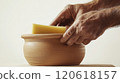 Close-up of potter's hands finishing clay pot with sponge - craftsmanship and artistry 120618157