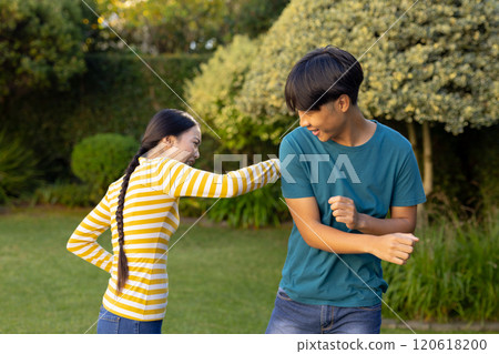 Playing and laughing, two young asian brother and sister enjoying time together outside 120618200