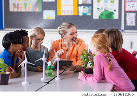 In school, female teacher with tablet, engaging diverse students with wind turbines and plants 120618360