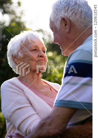 Happy caucasian senior couple embracing and looking at themselves in sunny garden, copy space Happy caucasian senior couple embracing and looking at themselves in sunny garden, copy space 120618545