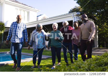 Happy diverse group of senior friends walking next to pool in sunny garden Happy diverse group of senior friends walking next to pool in sunny garden 120618549