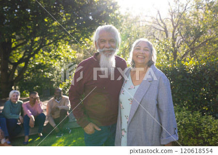 Happy biracial couple of senior friends embracing and smiling in sunny garden 120618554
