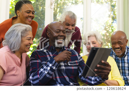 Happy diverse group of senior friends having video call and laughing in sunny living room Happy diverse group of senior friends having video call and laughing in sunny living room 120618624