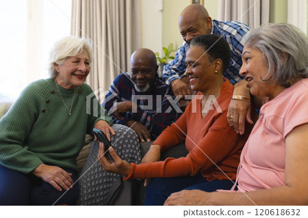 Happy diverse group of senior friends having video call and smiling in sunny living room Happy diverse group of senior friends having video call and smiling in sunny living room 120618632