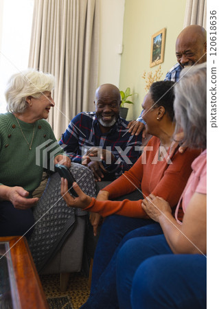 Happy diverse group of senior friends having video call and discussing in sunny living room 120618636