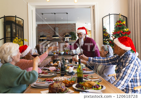Happy biracial senior man toasting with friends at christmas dinner in sunny dining room Happy biracial senior man toasting with friends at christmas dinner in sunny dining room 120618728