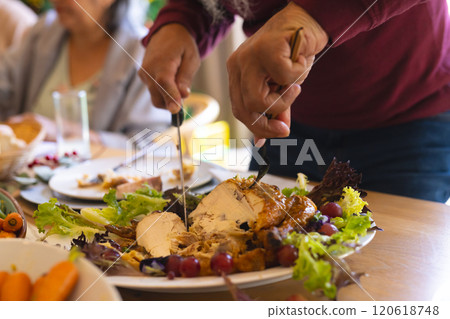 Hands of biracial senior man cutting meal at christmas dinner in sunny dining room Hands of biracial senior man cutting meal at christmas dinner in sunny dining room 120618748