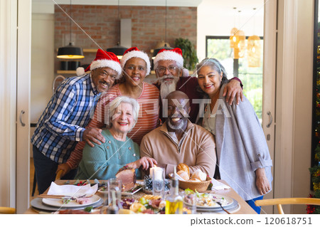 Happy diverse group of senior friends posing to picture at christmas dinner in sunny dining room 120618751