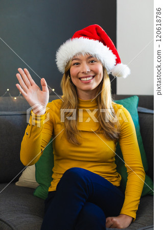 Happy caucasian woman in santa hat having video call and waving hand at christmas at home 120618786