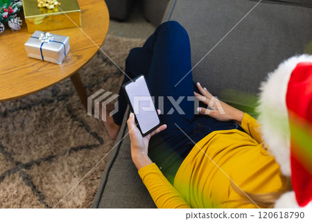 Happy caucasian woman in santa hat using smartphone with copy space at christmas at home Happy caucasian woman in santa hat using smartphone with copy space at christmas at home 120618790