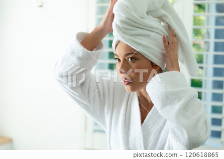 Happy caucasian woman in bathrobe holding towel on head in sunny bathroom Happy caucasian woman in bathrobe holding towel on head in sunny bathroom 120618865