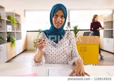 Portrait of happy biracial casual businesswoman with hijab having video call in creative office Portrait of happy biracial casual businesswoman with hijab having video call in creative office 120618928