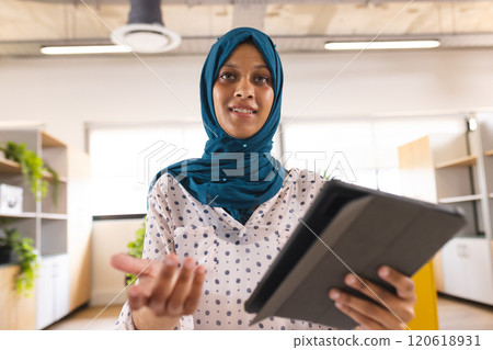 Portrait of happy biracial casual businesswoman with hijab having video call in creative office Portrait of happy biracial casual businesswoman with hijab having video call in creative office 120618931