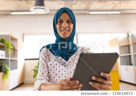 Portrait of happy biracial casual businesswoman with hijab having video call in creative office Portrait of happy biracial casual businesswoman with hijab having video call in creative office 120618933