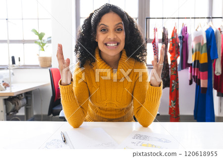Happy biracial female fashion designer having video call at desk in studio 120618955