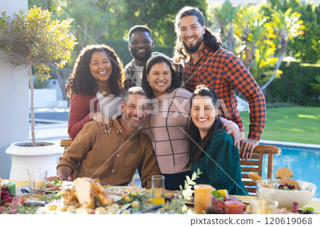 Happy diverse male and female friends posing during thanksgiving celebration meal in sunny garden 120619068