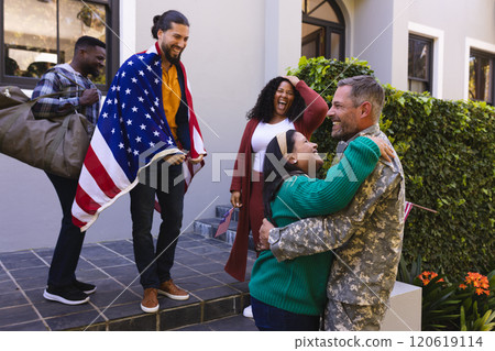Happy diverse friends with flags welcoming home male soldier friend Happy diverse friends with flags welcoming home male soldier friend 120619114