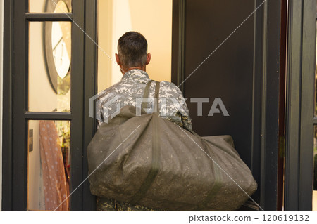 Caucasian male soldier in uniform returning home walking into house Caucasian male soldier in uniform returning home walking into house 120619132