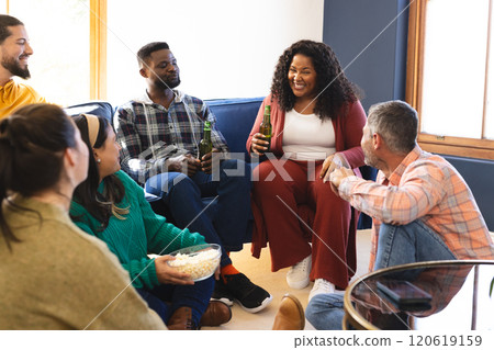 Happy diverse male and female friends talking, eating popcorn and drinking beer at home Happy diverse male and female friends talking, eating popcorn and drinking beer at home 120619159