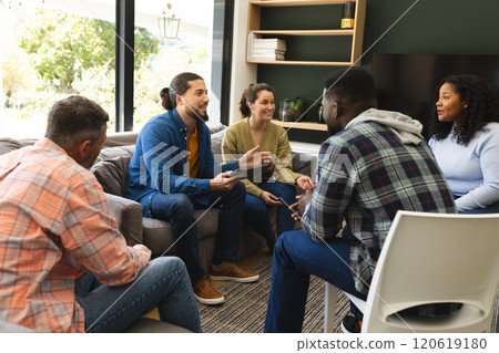 Diverse group of friends and male therapist with tablet in group therapy session 120619180