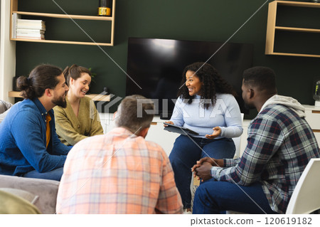 Diverse group of friends and female therapist with tablet in group therapy session Diverse group of friends and female therapist with tablet in group therapy session 120619182