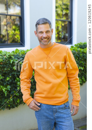 Happy caucasian man standing and smiling in front of house in sunny garden Happy caucasian man standing and smiling in front of house in sunny garden 120619245