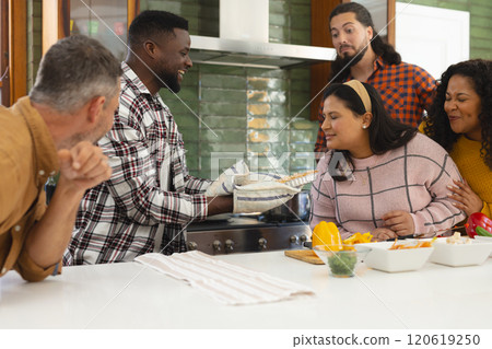Happy diverse male and female friends preparing meal in kitchen 120619250