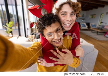 Portrait of happy diverse gay male couple wearing christmas hats and having video call at home Portrait of happy diverse gay male couple wearing christmas hats and having video call at home 120619383