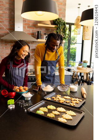 Happy diverse couple admiring freshly baked christmas cookies in kitchen, copy space Happy diverse couple admiring freshly baked christmas cookies in kitchen, copy space 120619443