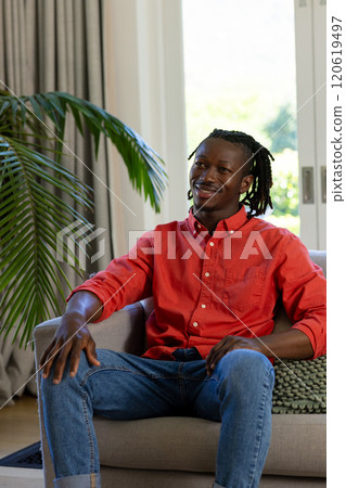 Happy african american man with dreadlocks sitting on couch in sunny living room, copy space Happy african american man with dreadlocks sitting on couch in sunny living room, copy space 120619497
