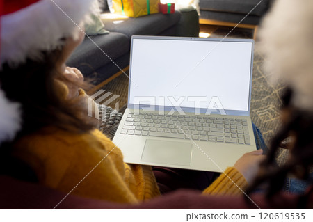 Diverse couple in christmas hats having laptop video call, copy space screen Diverse couple in christmas hats having laptop video call, copy space screen 120619535