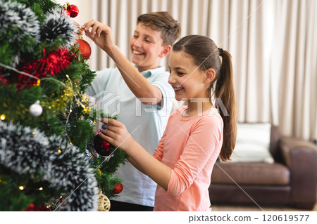 Caucasian boy and girl decorate a Christmas tree at home Caucasian boy and girl decorate a Christmas tree at home 120619577